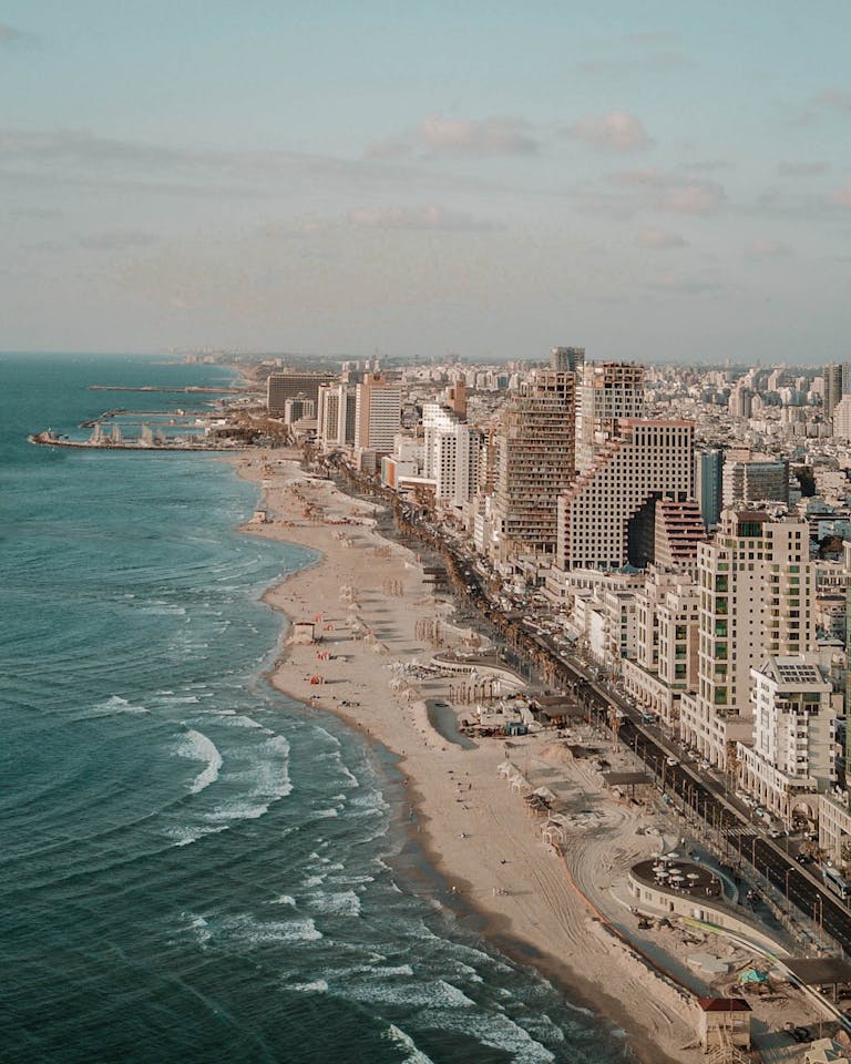 Aerial photo capturing Tel Aviv's urban skyline meeting the Mediterranean coastline.